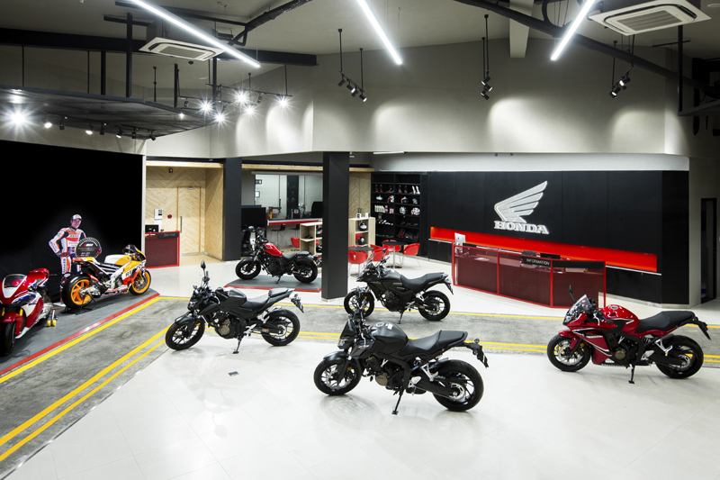 Khu vực trưng bày xe máy trong showroom với kệ phụ kiện gọn gàng phục vụ khách hàng