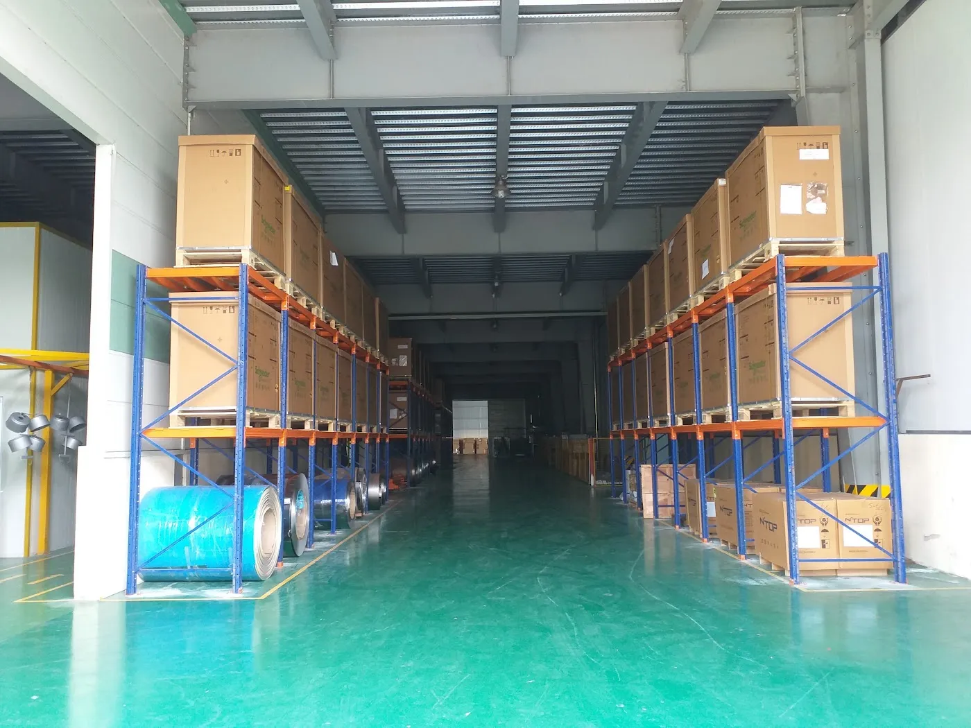Lối đi xe nâng giữa hai dãy kệ pallet chứa hàng thành phẩm, sàn sơn epoxy
