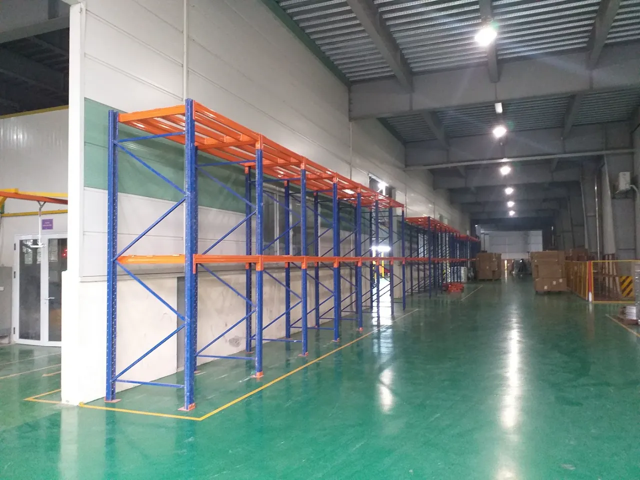 Row of pallet racking along the wall of a high-bay warehouse building